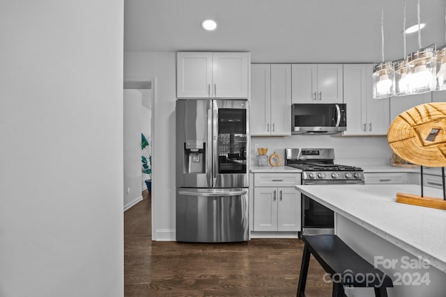 kitchen with white cabinets, pendant lighting, dark hardwood / wood-style floors, and appliances with stainless steel finishes