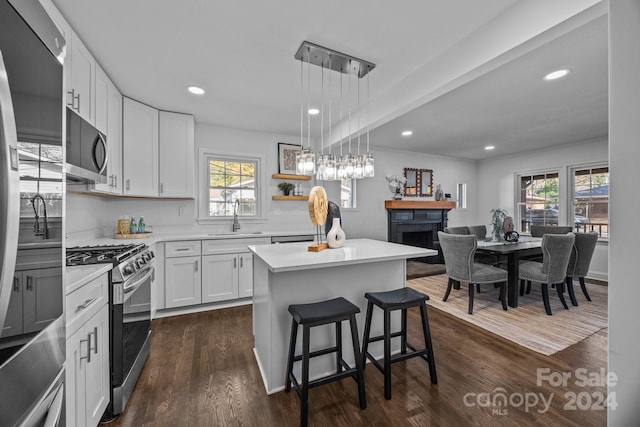 kitchen with appliances with stainless steel finishes, a center island, white cabinetry, and a wealth of natural light