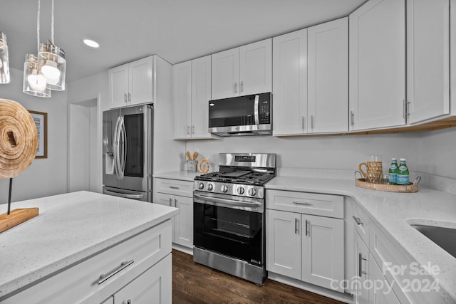 kitchen with dark hardwood / wood-style flooring, white cabinets, pendant lighting, and appliances with stainless steel finishes