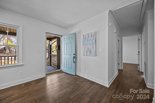 foyer entrance featuring a textured ceiling, ornamental molding, and dark wood-type flooring