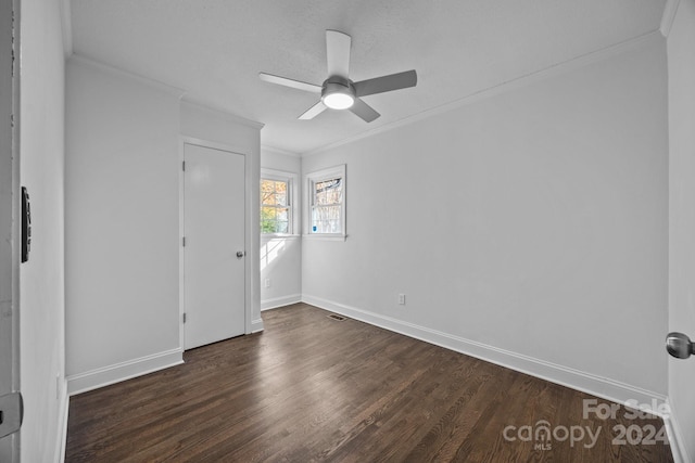 empty room featuring a textured ceiling, ceiling fan, crown molding, and dark wood-type flooring