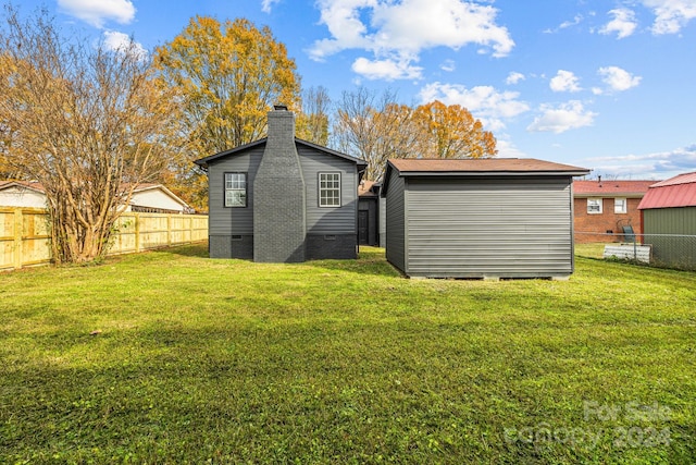 back of house with a lawn and a storage shed