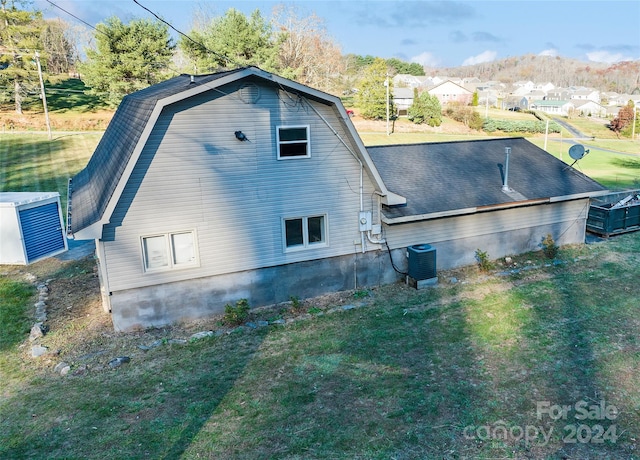 view of property exterior with a lawn and cooling unit