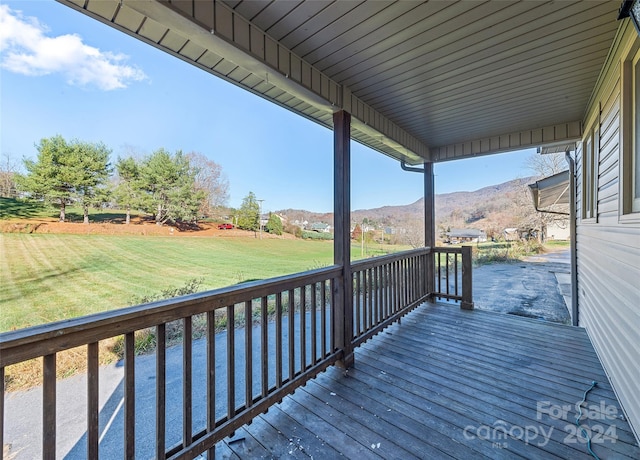 wooden deck featuring a mountain view and a lawn