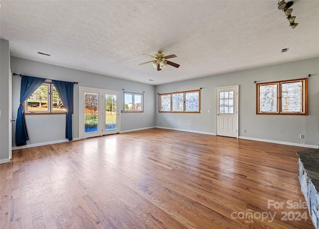 unfurnished living room featuring ceiling fan, wood-type flooring, and a textured ceiling