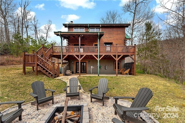 back of house with a fire pit, a patio area, a deck, and a lawn