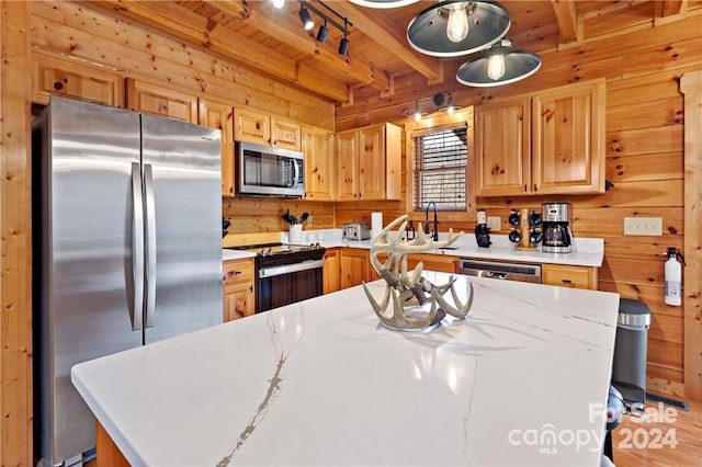 kitchen featuring appliances with stainless steel finishes, a center island, wood walls, and beam ceiling