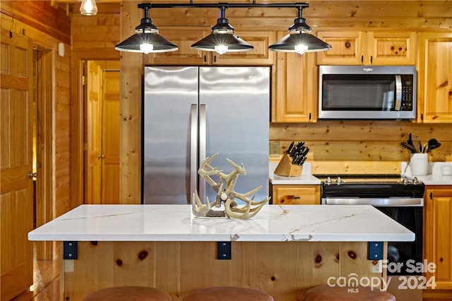 kitchen featuring light stone countertops, wood walls, pendant lighting, and stainless steel appliances