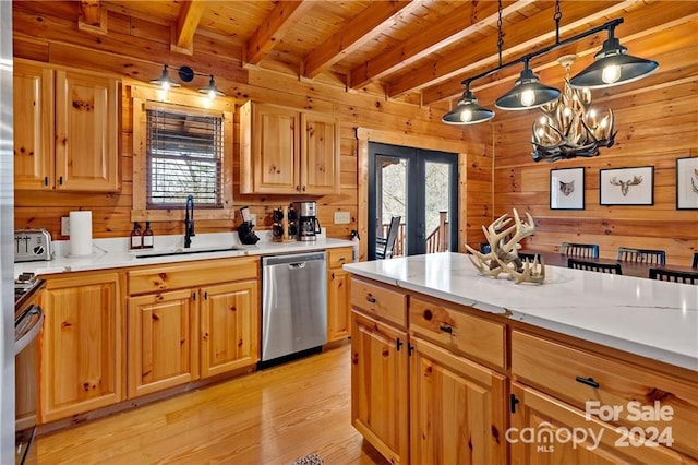 kitchen with sink, wood walls, decorative light fixtures, appliances with stainless steel finishes, and light wood-type flooring