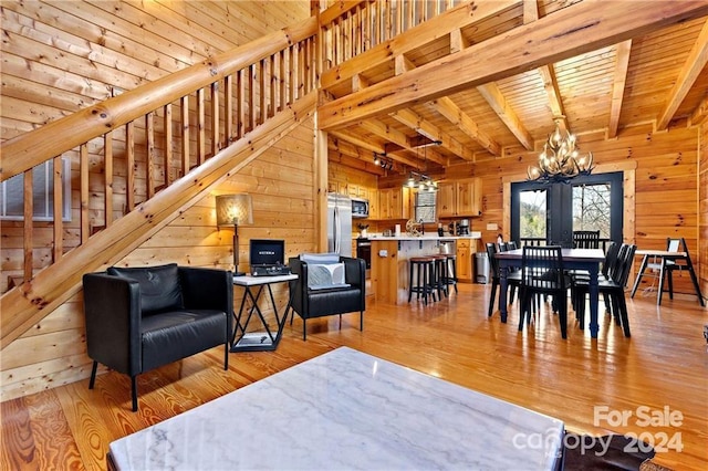 living room with beamed ceiling, light hardwood / wood-style flooring, wooden ceiling, and wood walls