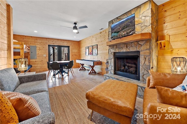 tiled living room with ceiling fan, wood walls, a fireplace, and pool table