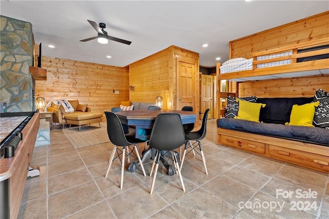 dining space with ceiling fan and wood walls