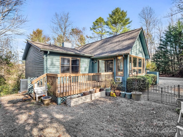 chalet / cabin with central air condition unit, a chimney, and a wooden deck