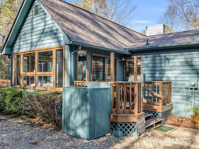 back of house featuring a sunroom, a shingled roof, and a chimney