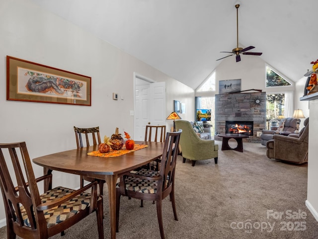 dining space with light carpet, high vaulted ceiling, ceiling fan, and a fireplace