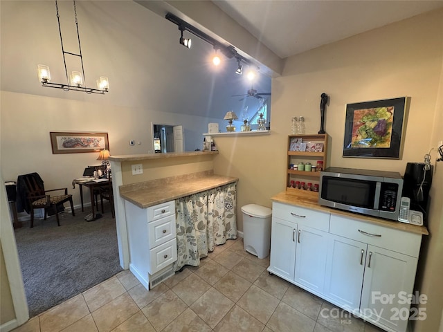 kitchen with light carpet, white cabinets, ceiling fan, stainless steel microwave, and a peninsula