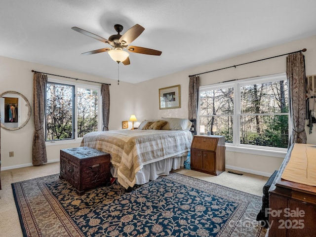 bedroom with light colored carpet, multiple windows, and baseboards