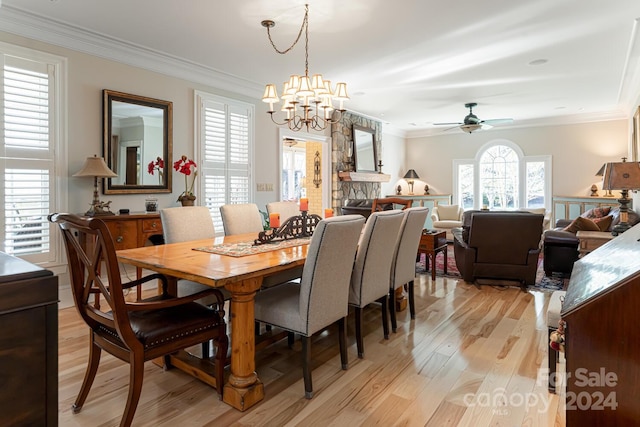 dining area featuring ceiling fan with notable chandelier, ornamental molding, a fireplace, and light hardwood / wood-style flooring