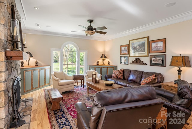 living room featuring a fireplace, light wood-type flooring, ceiling fan, and ornamental molding