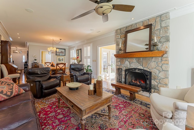 living room with a fireplace, ceiling fan with notable chandelier, and ornamental molding