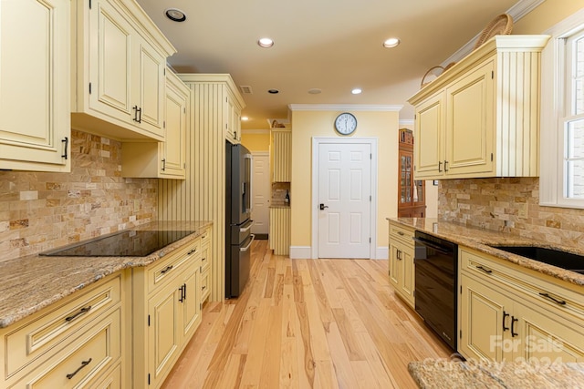 kitchen with black appliances, crown molding, light stone countertops, cream cabinetry, and light hardwood / wood-style floors