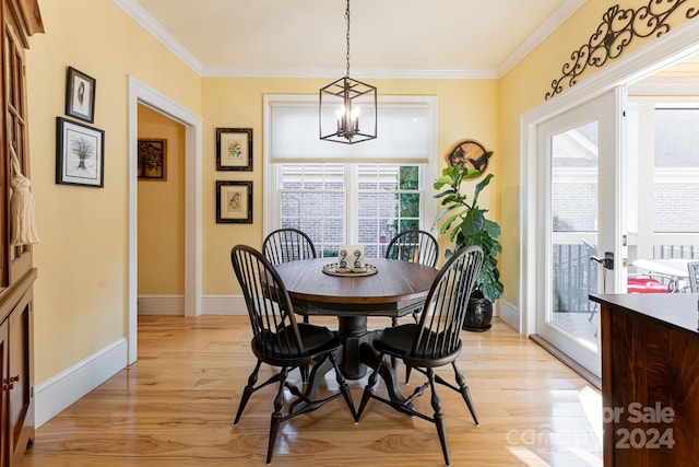 dining space featuring french doors, ornamental molding, a notable chandelier, and light wood-type flooring