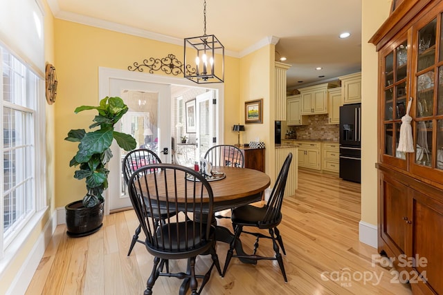 dining space featuring a chandelier, light wood-type flooring, and ornamental molding