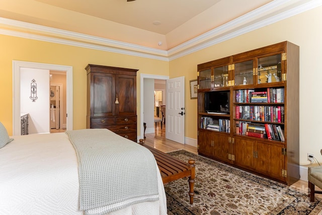 bedroom featuring wood-type flooring, ornamental molding, and ensuite bath