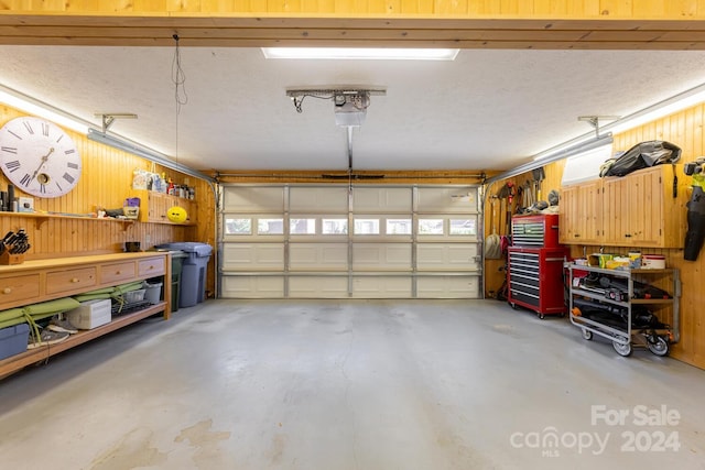 garage featuring a workshop area, wood walls, and a garage door opener