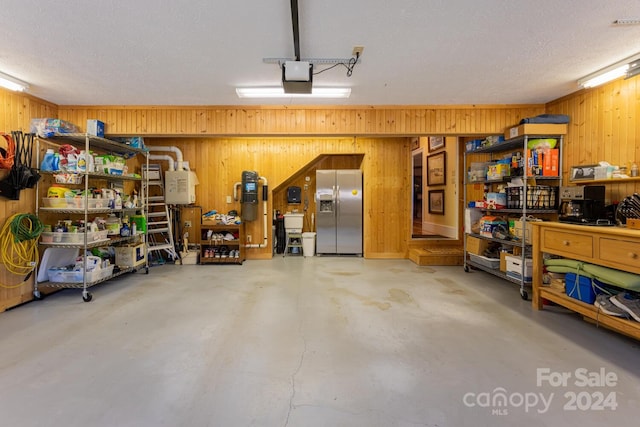 garage featuring stainless steel fridge, sink, a garage door opener, and wood walls