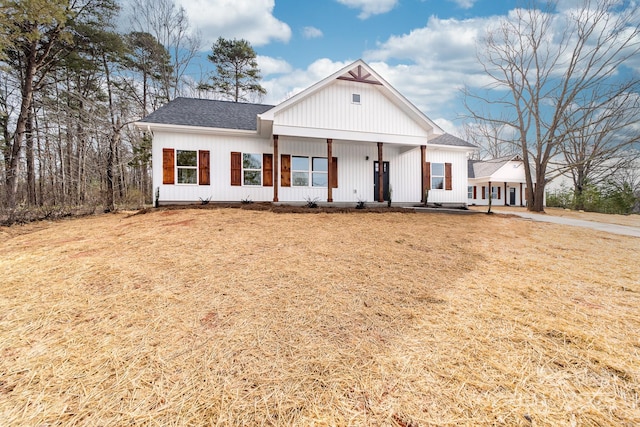 modern farmhouse with a porch and a shingled roof