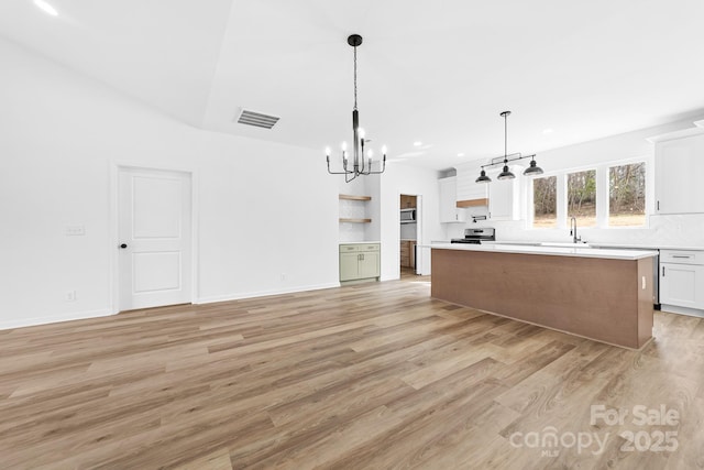 kitchen with visible vents, light wood-style flooring, a sink, light countertops, and a notable chandelier