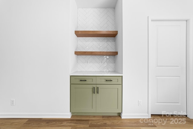 bar featuring baseboards, tasteful backsplash, and light wood finished floors