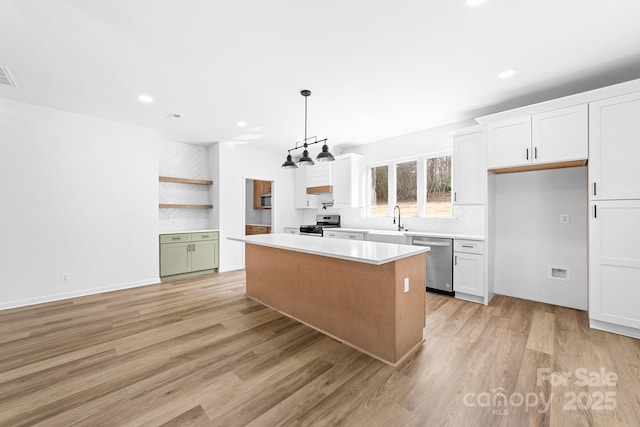 kitchen with open shelves, a sink, light countertops, appliances with stainless steel finishes, and white cabinetry
