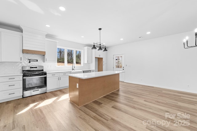 kitchen with light countertops, light wood-type flooring, stainless steel gas stove, and a kitchen island