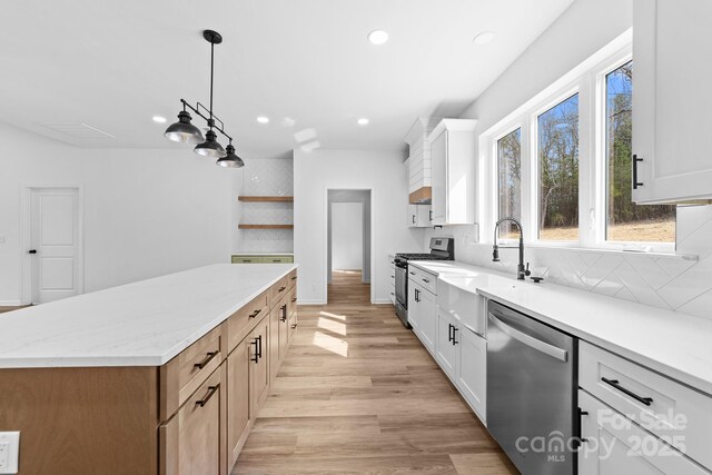 kitchen featuring light wood finished floors, open shelves, decorative backsplash, appliances with stainless steel finishes, and a center island