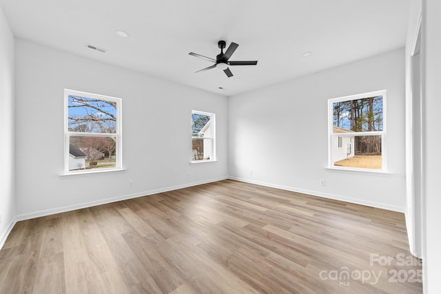 empty room featuring visible vents, ceiling fan, baseboards, and light wood-style floors