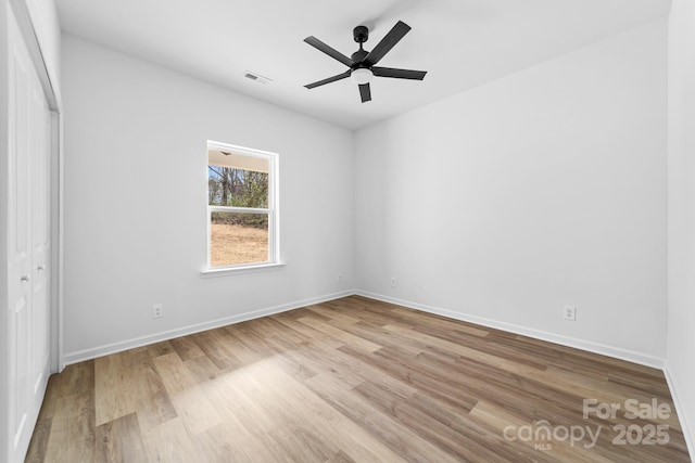 unfurnished bedroom with a closet, visible vents, baseboards, and wood finished floors