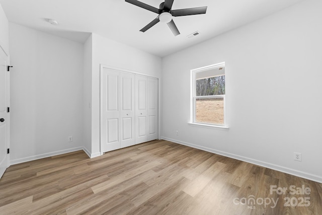 unfurnished bedroom featuring visible vents, baseboards, light wood-style floors, a closet, and a ceiling fan