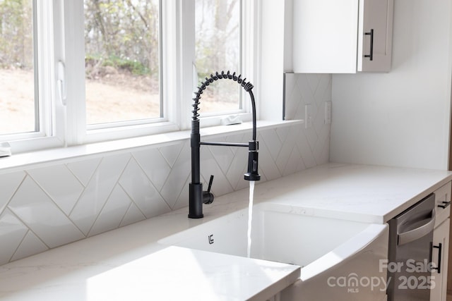 details featuring stainless steel dishwasher, white cabinetry, and a sink