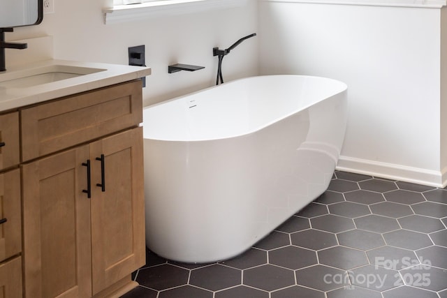 full bathroom with tile patterned floors, baseboards, a freestanding bath, and vanity