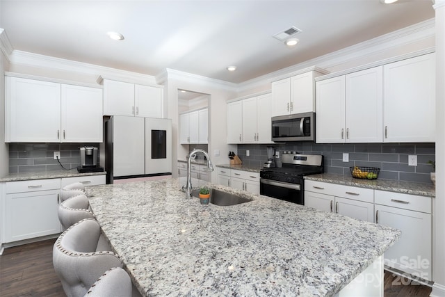 kitchen featuring white cabinets, an island with sink, stainless steel appliances, and sink