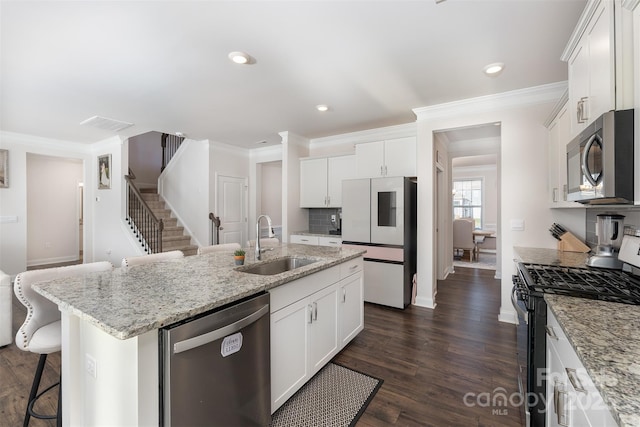 kitchen featuring a kitchen island with sink, sink, light stone countertops, appliances with stainless steel finishes, and white cabinetry