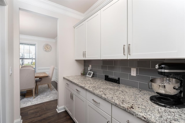 bar with white cabinetry, dark wood-type flooring, tasteful backsplash, light stone counters, and crown molding