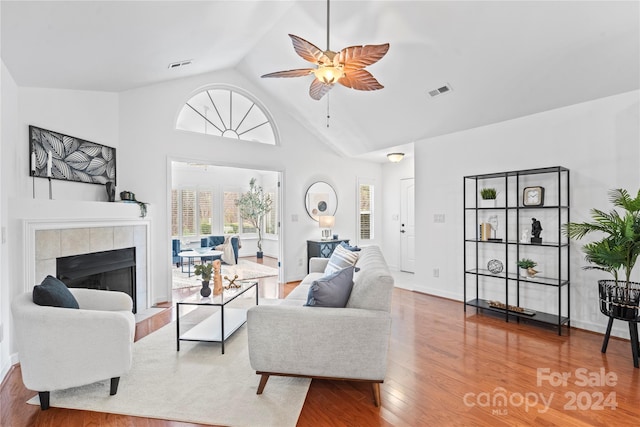 living room featuring a tile fireplace, hardwood / wood-style floors, high vaulted ceiling, and ceiling fan