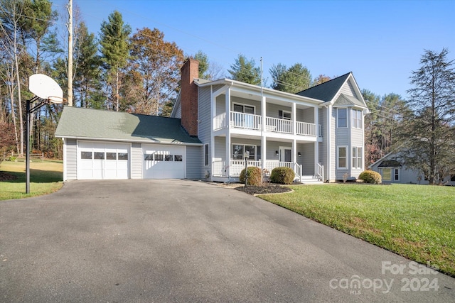 view of property with a porch, a balcony, a front yard, and a garage