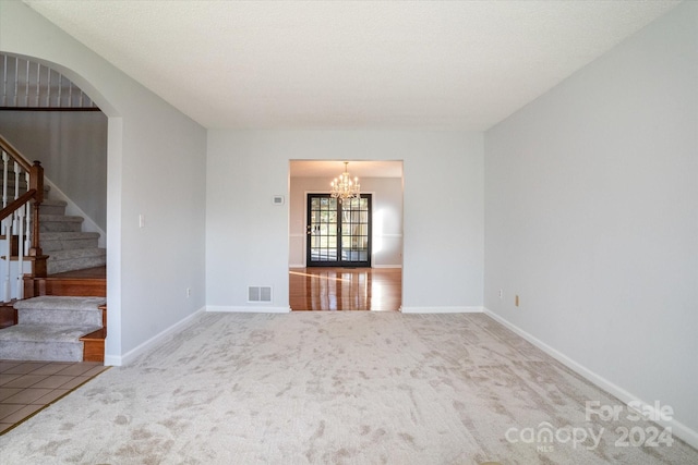 spare room with carpet flooring, a textured ceiling, and a chandelier