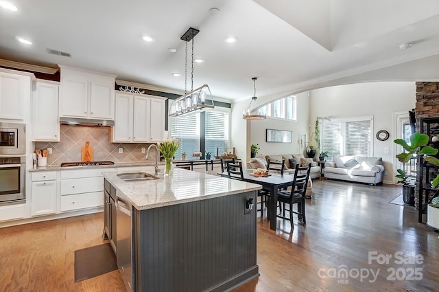 kitchen with stainless steel appliances, open floor plan, white cabinetry, and a sink