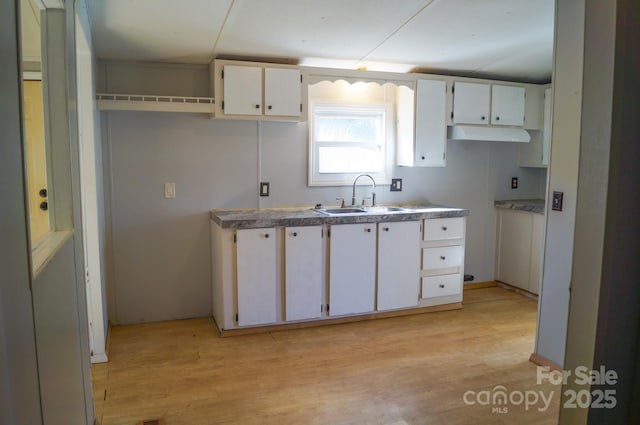 kitchen with white cabinets, light wood-type flooring, and sink