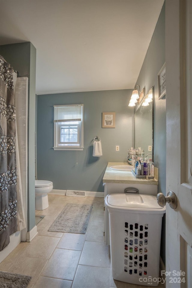 full bathroom with tile patterned flooring, vanity, toilet, and shower / bath combo with shower curtain